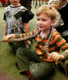 A birthday party with a 
         child holding a snake around his neck